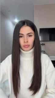 Кадр из видео с крупным планом молодой женщины в светлом свитере; вероятно автор рилса, нейтральный фон и фронтальная съёмка лица.