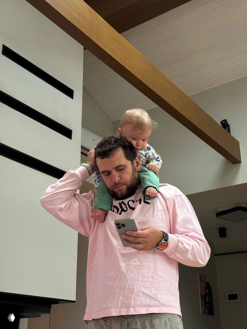 Отец с ребёнком на плечах в светлом лофте с деревянными балками — кадр домашней рутины и совместного времени в интерьере дома.