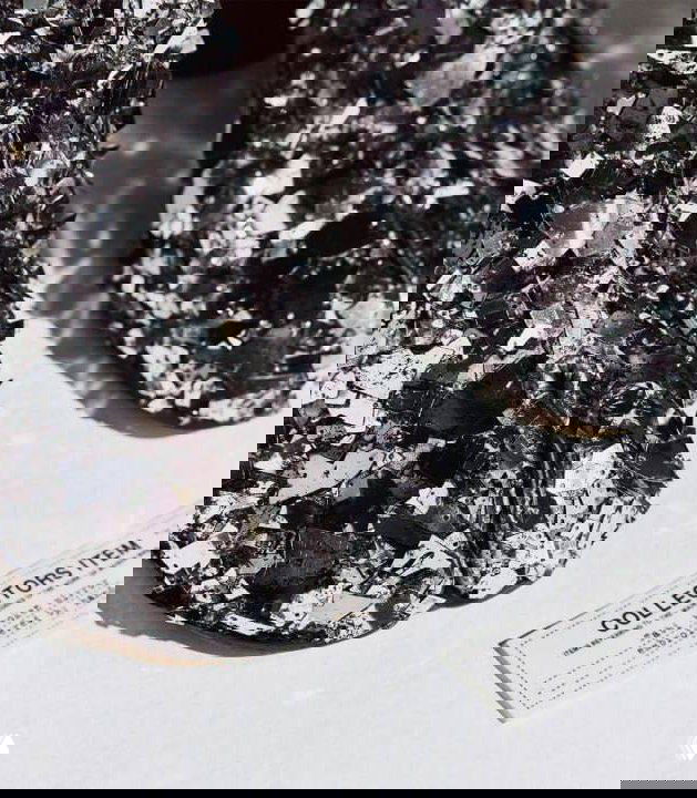 Крупный план покрытия обуви: пайетки, металлические детали и крупные осколки битого стекла, создающие фактурную сверкающую поверхность таби.