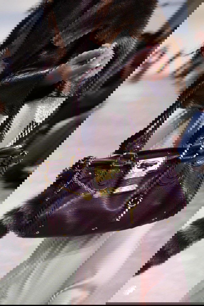 Крупный план бордовой (винной) сумки Chloé Paddington на подиуме с золотым замком и цепочной подвеской, видна текстура кожи