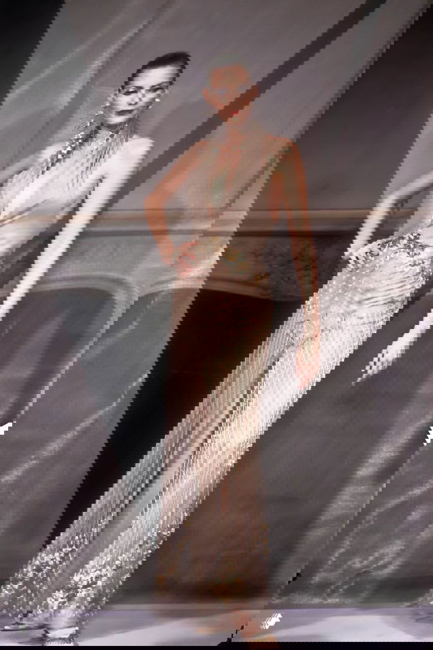 Модель в полупрозрачном бежевом платье с бахромой и золотистыми деталями; вечерний образ с показа Valentino, 1998.