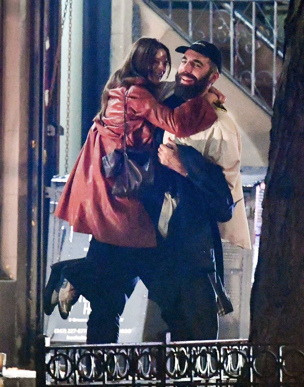 Кадр папарацци: Эмили Ратаковски запрыгивает на мужчину, они смеются и обнимаются на тротуаре в ночном освещении