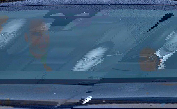 Водитель за рулём и ребёнок на переднем сиденье в салоне автомобиля, ночной кадр папарацци из окна машины во время поездки.