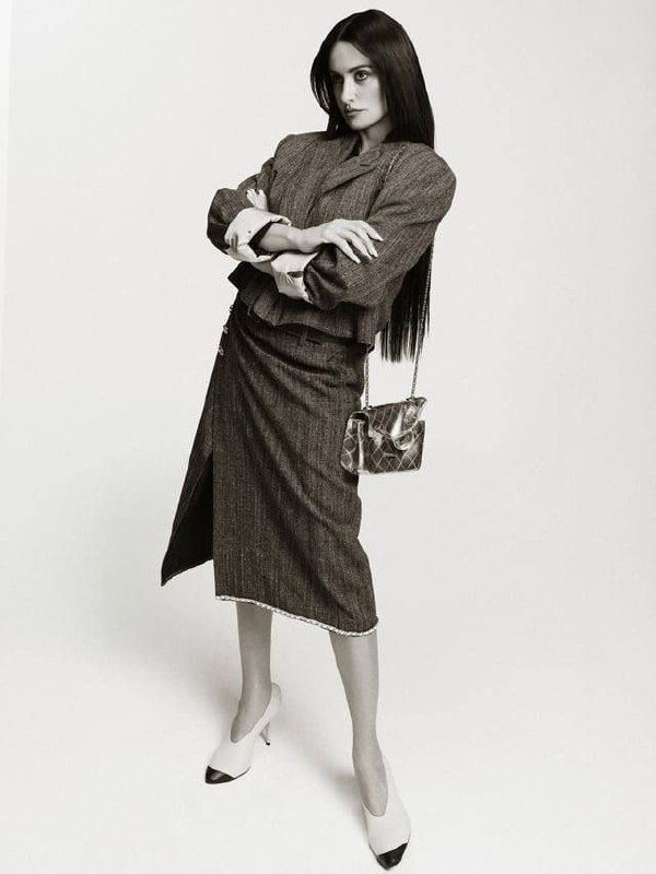 Монохромный кадр: Пенелопа Крус в костюме и юбке, сумка через плечо, строгий силуэт и винтажная эстетика в студии.