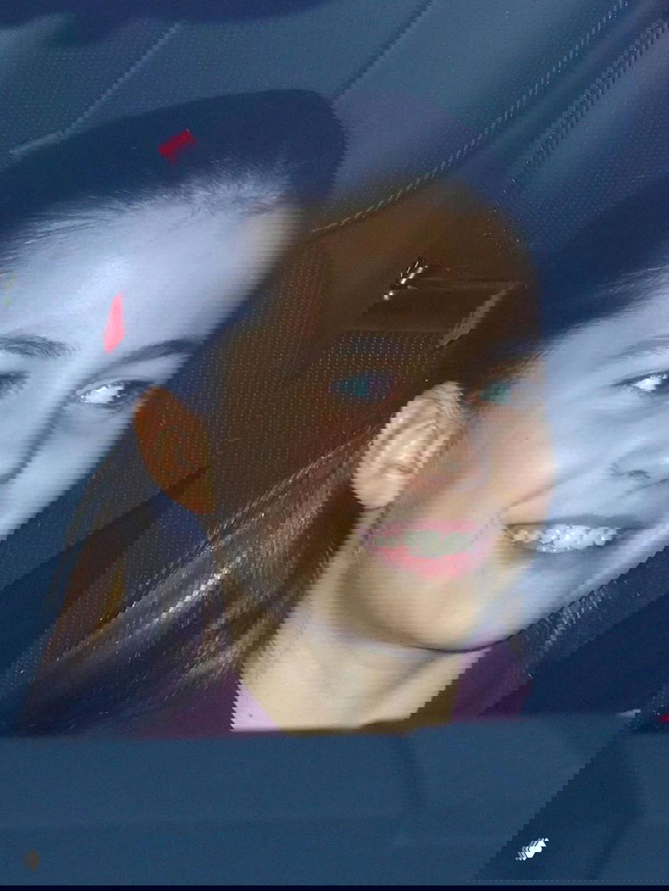 Крупный портрет юной пассажирки в автомобиле: лицо ребёнка видно через окно, кадр сделан папарацци во время поездки на ужин.