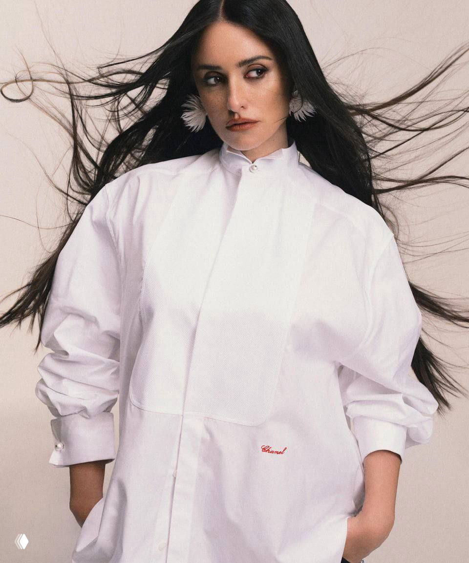 Пенелопа Крус в белой рубашке, волосы развеваются; глянцевый кадр подчёркивает силуэт, жест и атмосферу съемки для журнала.