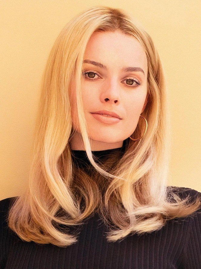 Студийный портрет женщины с распущенными светлыми волосами и серьгой-кольцом на нейтральном бежевом фоне, мягкое освещение, фасадный план.