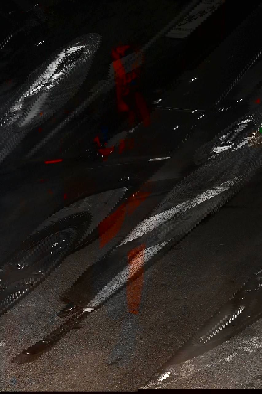 Ночной снимок: девушка в прозрачном кружевном наряде и массивных ботинках идёт по тёмной улице, выразительный контраст тканей.