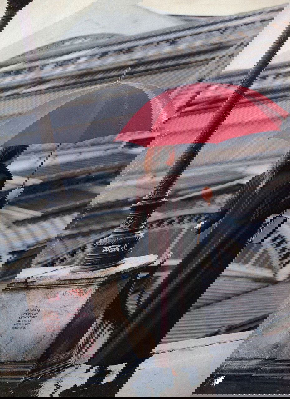 Кадр со спины: модель под красным зонтом на фоне крыши вокзала, дождливая сцена в стиле 90-х, акцент на силуэте и аксессуарах.