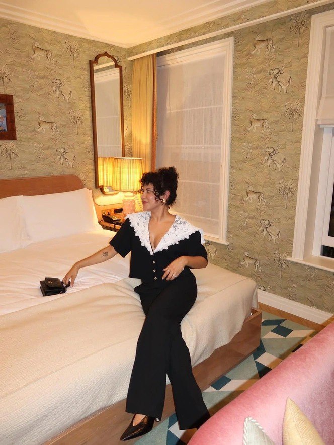 Интерьерный кадр: женщина в чёрно‑белом комплекте с большим белым воротником, создающим винтажный силуэт в современной съёмке.