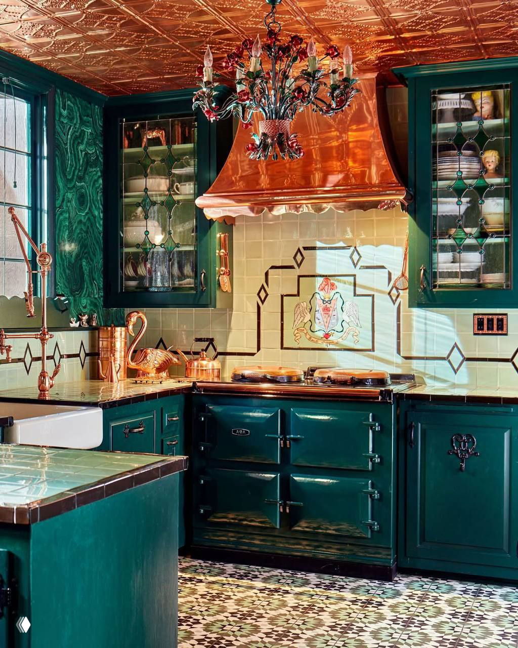 Кухня с глубокими зелёными шкафами, мраморно-зелёной плиткой и медным капюшоном над плитой — декоративный и насыщенный интерьер.