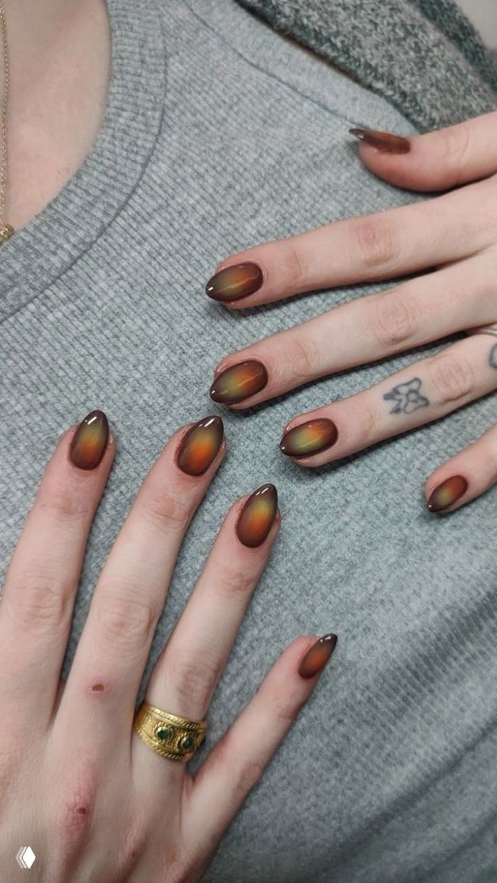 Пара рук с овальными ногтями в тёплом коричнево‑оранжевом хамелеонном градиенте на приглушённом фоне свитера, фото из подборки маникюра.
