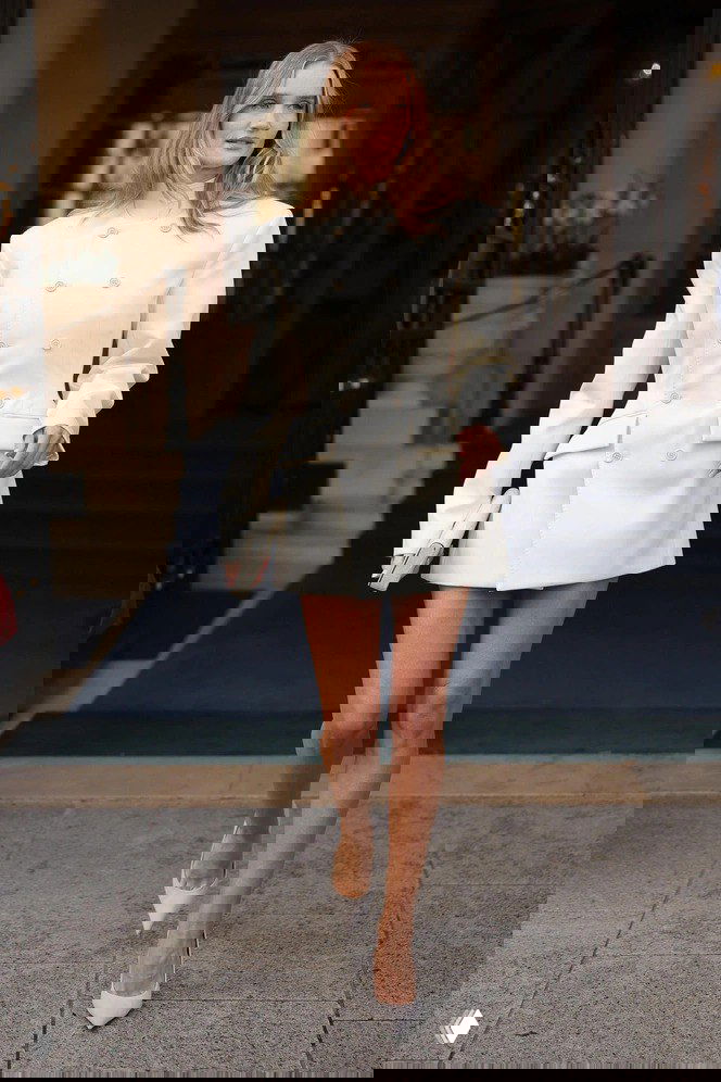 Роузи Хантингтон‑Уайтли в белом платье‑пиджаке с акцентированными плечами и клатчем — минималистичный праздничный образ на улице