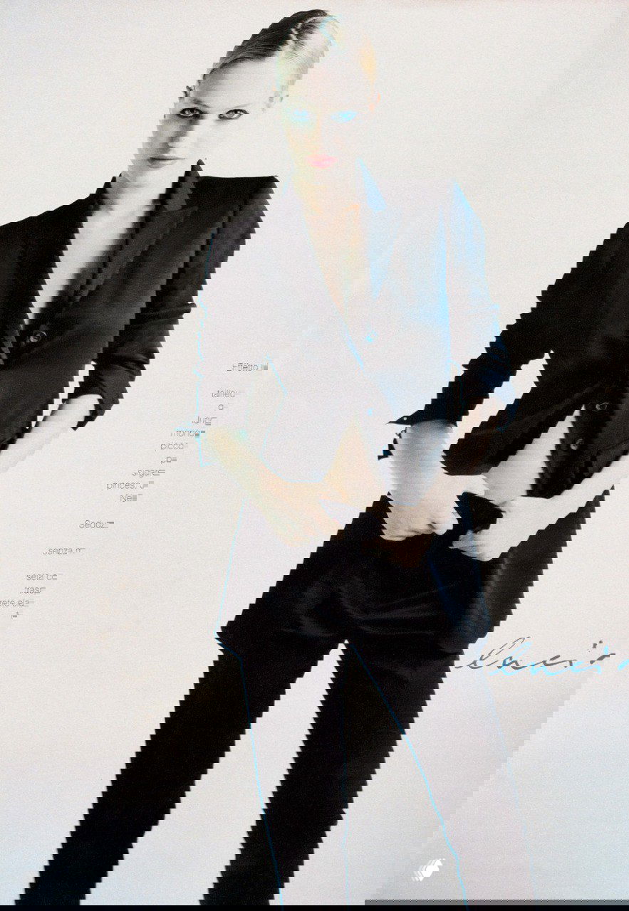 Модель в тёмном костюме на светлом фоне: повышенный контраст, строгая мужская стилистика в женском исполнении, fashion‑портрет в студии.