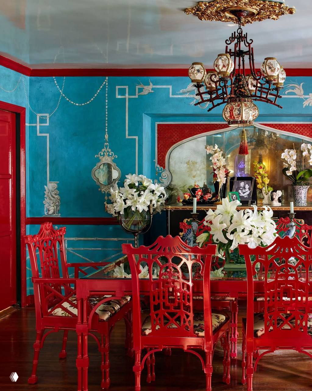 Столовая в ярко-голубых и красных тонах с китайскими мотивами в мебели и обоях, большой стол и красные стулья — эклектичный декоративный ансамбль.