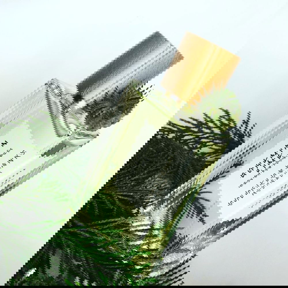 Прямоугольный флакон Goldfield & Banks Bohemian Lime со светло‑зелёной жидкостью в окружении хвои — свежий цитрусовый образ рекламного кадра.