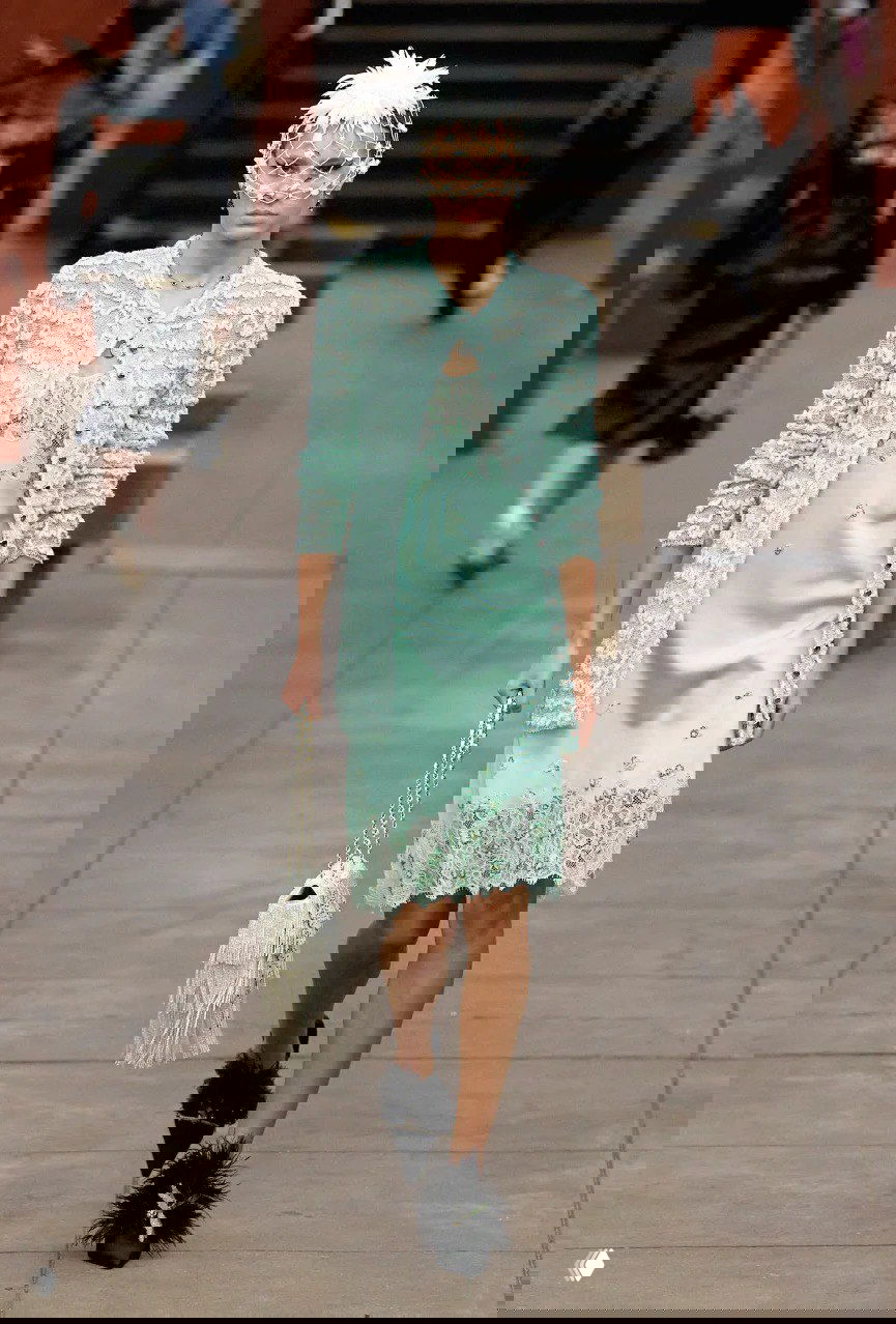 Модель в мятном кардигане и платье нежно‑ментолового оттенка проходит по подиуму, в руках у неё сумка и сетчатая головная деталь — показ Chanel.