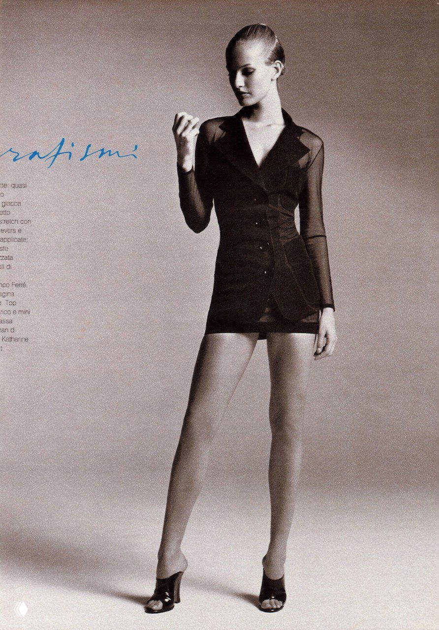 Полнорастовый кадр: модель в прозрачном и многослойном наряде, строгая поза на нейтральном фоне, стилистика фэшн‑съёмки 1995 года.