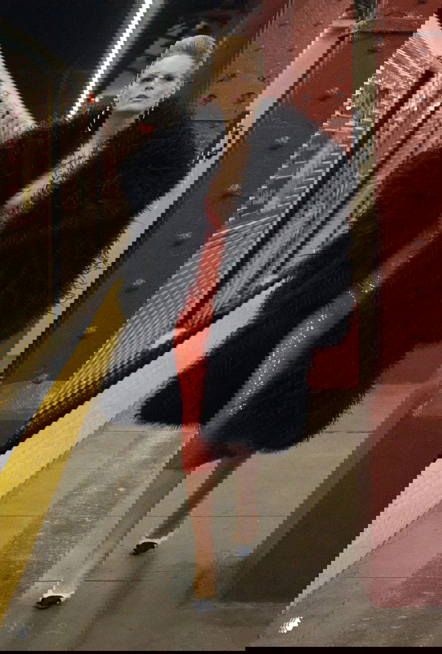 Модель в объёмной чёрной шубе и красном блестящем платье идёт по станции нью‑йоркского метро: драматичный образ в шоу Chanel Матье Блази.