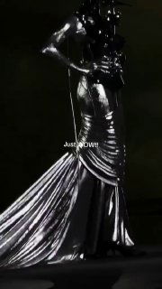 Кадр видео: обтягивающее металлическое кутюрное платье Роберта Вуна, глянцевая ткань, драпировка и подчёркнутый силуэт модели