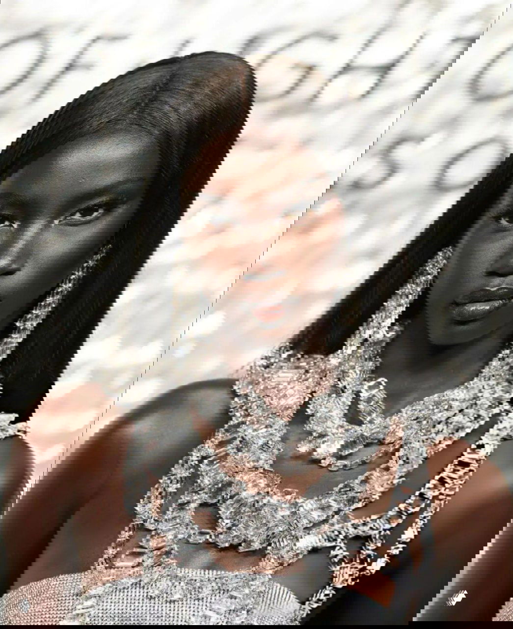 Крупный план лица модели с ровными волосами и массивным украшением из прозрачных кристаллов, подчёркивающим юбилей Swarovski.