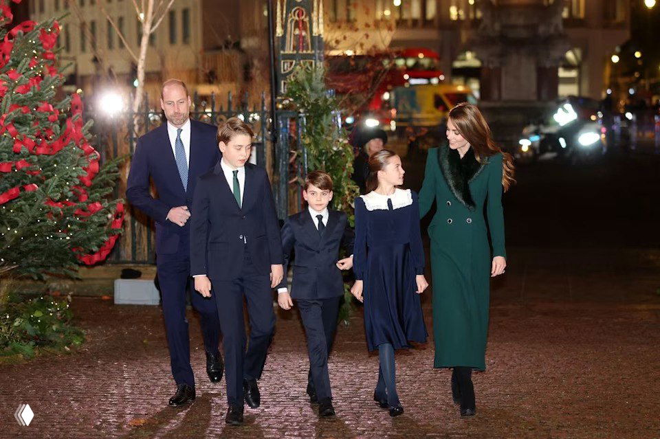 Семья в вечерних нарядах идёт по мостовой рядом с украшенной рождественской елью и светящимися гирляндами