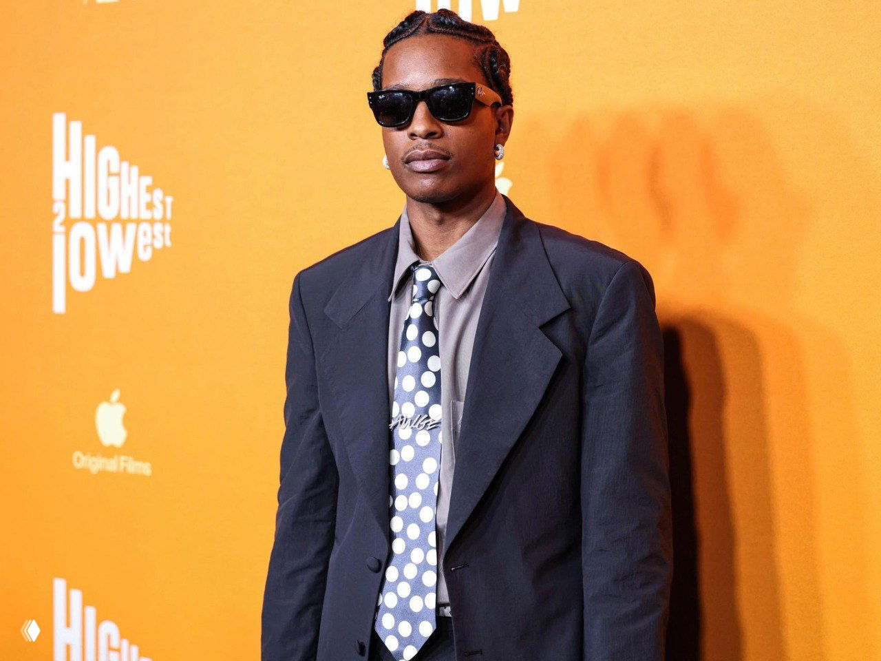 Фото A$AP Rocky в пиджаке и солнцезащитных очках на оранжевом фоне — иллюстрация новости о назначении амбассадором Chanel.