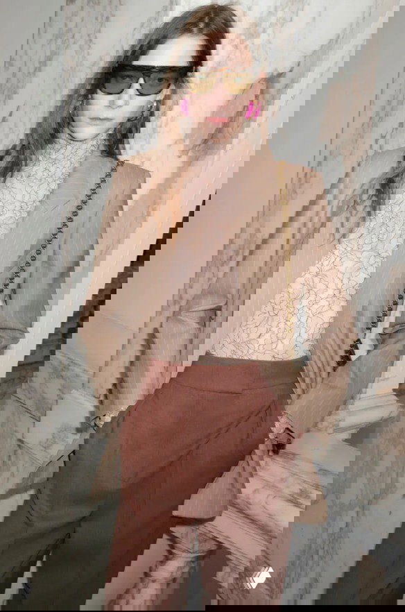 Модель в бежевом пиджаке и кружевной водолазке в сочетании с широкими брюками — деловой ретро‑лук с модными контрастами Valentino.