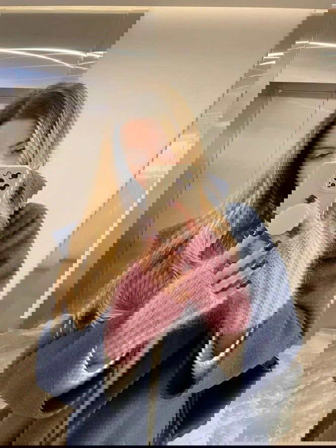 Крупный план селфи: синее пальто и пушистые розовые митенки на руках держат смартфон, подчёркивая акцентные аксессуары в образе.