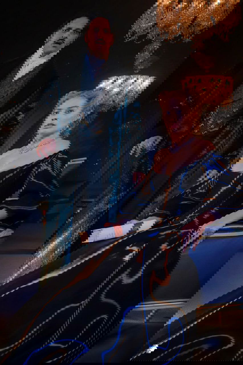 Мужской и женский костюмы в темном интерьере: лаковый черный наряд с глубоким декольте и мужской викторианский костюм под люстрой.