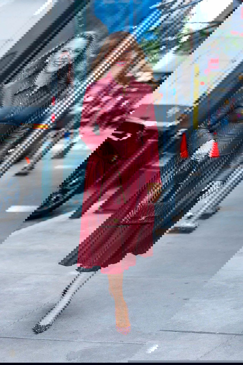 Блейк Лайвли в винно-красном кожаном платье с корсетом и сумкой, идёт по улице Нью-Йорка — образ из коллекции Sergio Hudson.