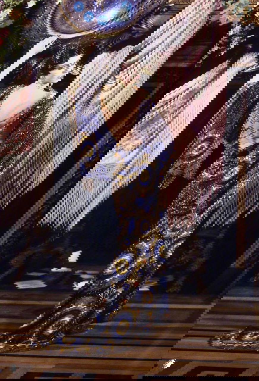 Модель в узорчатом синем платье с открытой спиной и обильной отделкой бисером на фоне драпировок — эстетика кутюрного спектакля Dior 1998.