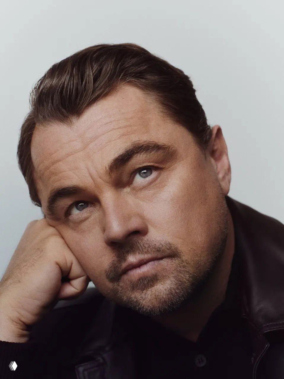 Портретная фотография взрослого мужчины в задумчивой позе, крупный план лица, мягкое студийное освещение и нейтральный фон.