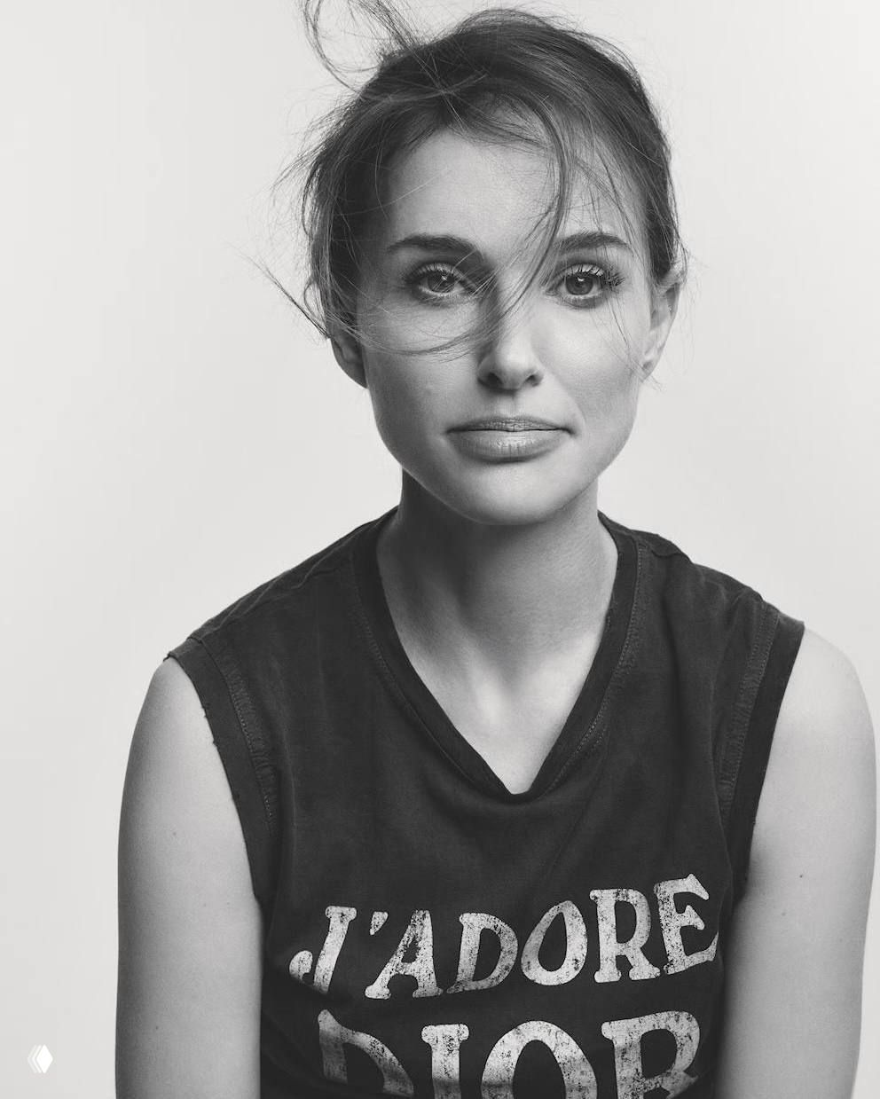 Чёрно-белый портрет актрисы в футболке с надписьью, спокойный выражение лица, волосы развеваются, минималистичная стилизация и акцент на глазах.