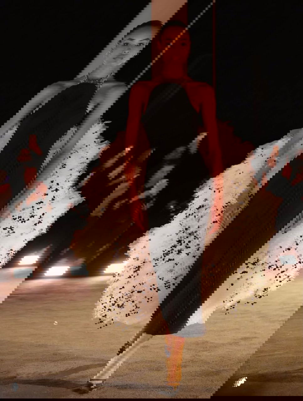 Модель в строгом черном платье с объемным белым хвостом-органзой по бокам, контрастные фактуры на кутюрном показе Schiaparelli.