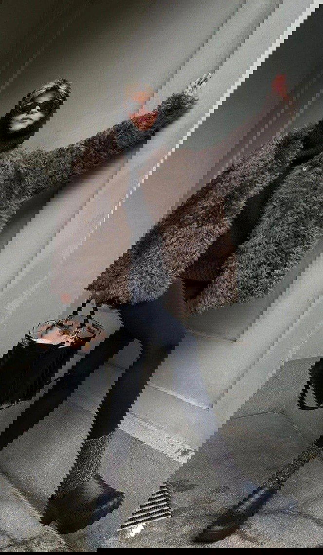 Девушка в кудрявой шубе из овчины коричневого оттенка, сочетание с тёмными лосинами и платформенной обувью, стильный городской лук