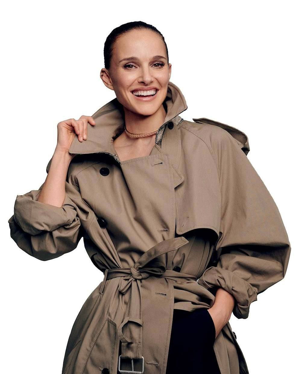 Портрет в светлом плаще цвета хаки: улыбка, рука за воротником, умеренно формальная поза в духе журнальной модной съёмки.