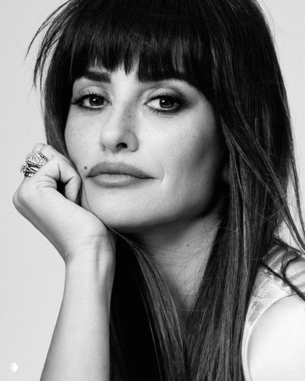 Чёрно‑белый крупный портрет женщины в студийной фотосессии: естественный макияж, чёлка, рука под подбородком, кольцо и задумчивый выразительный взгляд