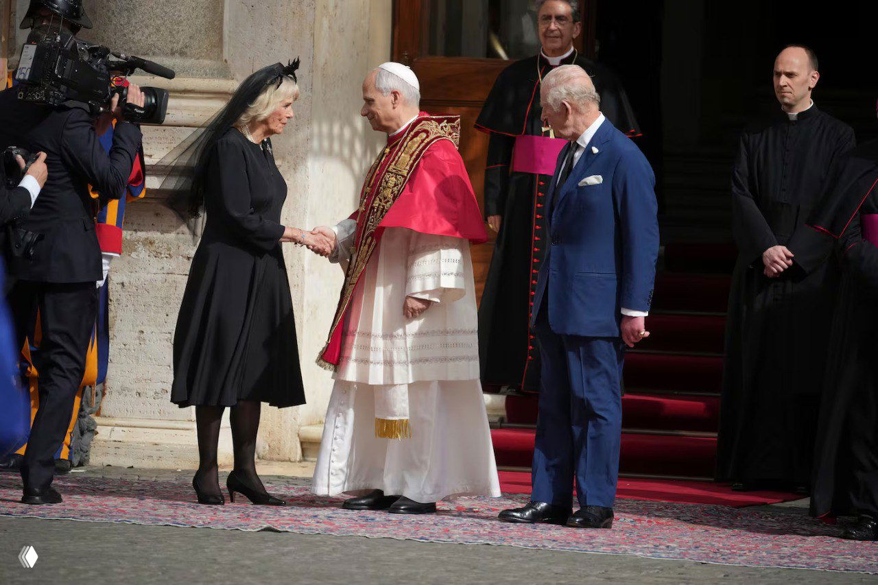 Рукопожатие женщины в чёрном платье и мантилье с представителем папской канцелярии на фоне ступеней и швейцарской гвардии.