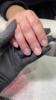 Рука клиента в руках мастера в перчатках; этап подготовки ногтей к маникюру мягкого квадрата, вид крупным планом.