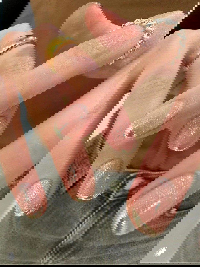 Фрагмент рук с блестящими розово-персиковыми ногтями и зеркальными золотистыми френч-акцентами — вариант для праздничного зимнего образа.