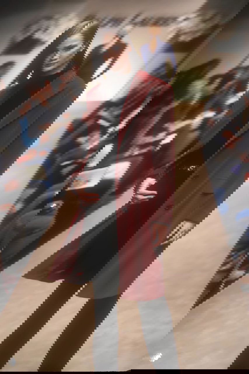 Модель в тёмно-красном пальто и чёрных брюках на подиуме Ralph Lauren; сочетание насыщенного цвета и сдержанной основы коллекции 1996.