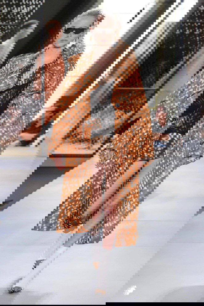 Модель на подиуме в длинном плаще и мини-платье с заметным пятнистым принтом 'Бэмби'; съёмка показа высшей моды и стилизованный лук.