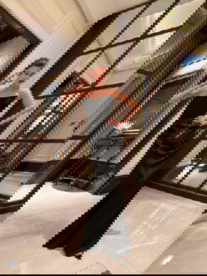 Женский вечерний образ в полностью чёрном платье в интерьере — пример приёма Total Black, который может выглядеть элегантно или мрачно.