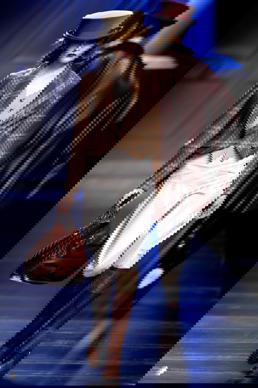 Фигура на подиуме в твидовом пиджаке и белых брюках с высокой талией — сочетание классики и ориентировочного ретро‑стиля в показе Dior 2010.