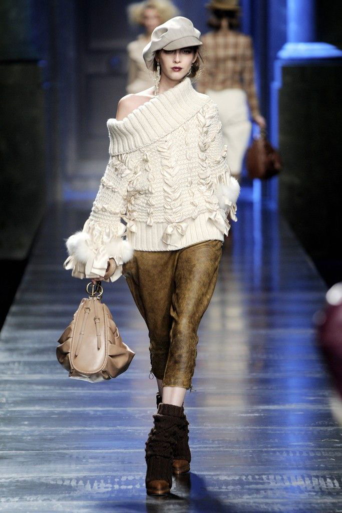 Пуловер с крупной вязкой, укороченные кожаные брюки и сумка в руках модели — уютные фактуры и аксессуары в коллекции Dior осень‑зима 2010.