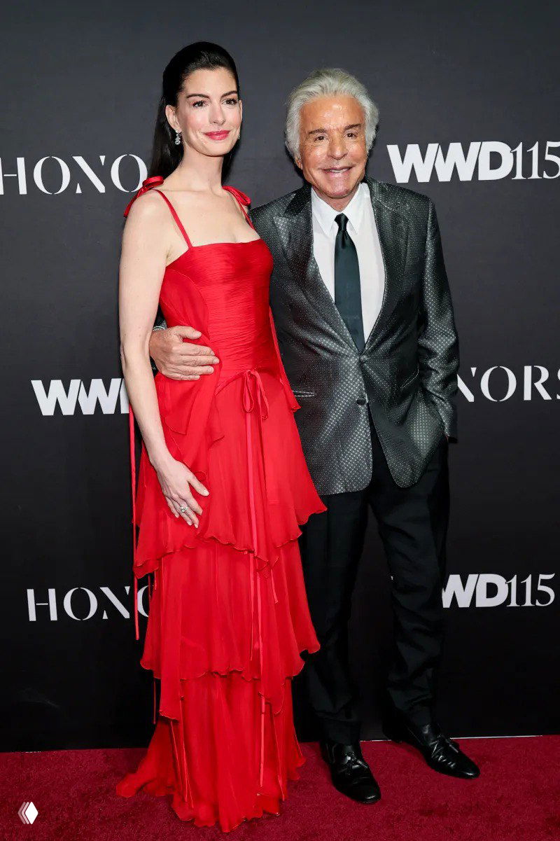 Актриса в многослойном красном платье Valentino позирует на ковровой дорожке WWD Honor Awards 2025 в Нью‑Йорке.