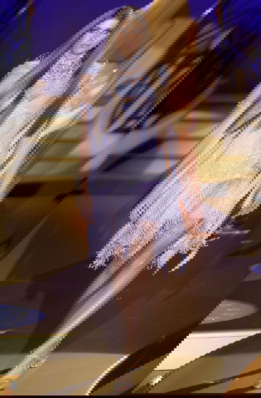 Модель в светло-лиловом коротком платье с бисером и бахромой, игривый кутюрный образ Versace 2004 на подиуме с почти театральной постановкой света.