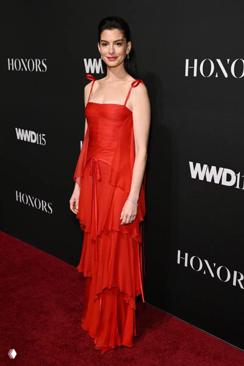 Актриса в облегающем красном платье Valentino позирует у пресс‑волла с логотипом WWD Honor Awards 2025 в Нью‑Йорке.