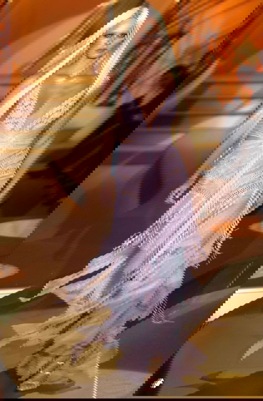 Длинное сиренево-розовое платье с ажурными и струящимися деталями, модель в движении демонстрирует лёгкость тканей и характерную для Versace 2004 драпировку.